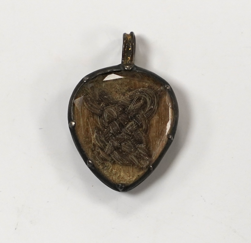 An 18th century gilt metal heart shaped mourning pendant, with engraved inscription, 'CARna DERBY DIED DEC 11th, 1762' and plaited hair beneath a glazed panel verso, 27mm.